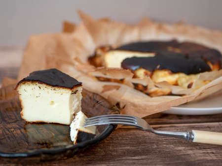 Basque burnt cheesecake slice with a burnished exterior and a creamy custardy interior on a brown...