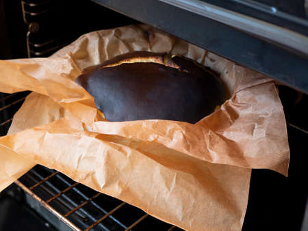 Taking freshly baked Basque burnt cheesecake out of the oven. Cooking the homemade caramelized round cake during the lockdownの写真素材