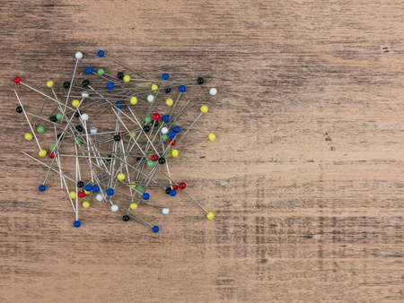 Colored straight pins on wooden table, copy space. Ball-point pins used to fasten pieces of cloth or paper together. Tool to the sewistの写真素材