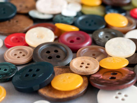 Round sewing buttons of different colours and sizes, close up. Variety of colored flat buttons with two or four holes, selective focusの写真素材