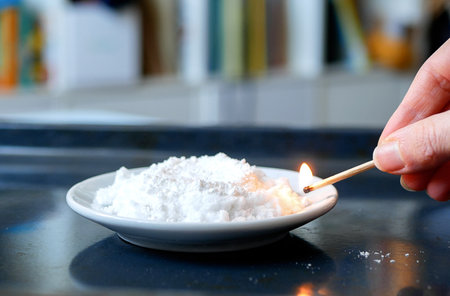 Hand ignites urotropin mixed with calcium gluconate, selective focus. Concept of chemistry lesson,...