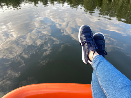 Legs on the edge of the catamaran or boat, copy space. Person dangling down the feet above water. Concept of leisure on natureの写真素材