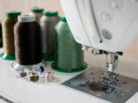 Sewing threads, bobbins and foot with needle of sewing machine, selective focus. Concept of...