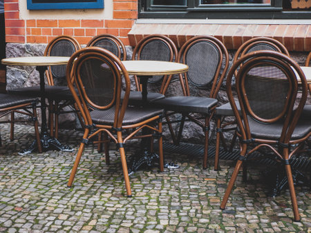 Round tables and chairs with bent backs and legs await visitors on the cafe's summer terrace, selective focusの写真素材