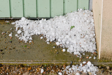 A pile of hailstones against a garage door and a corner of a wall