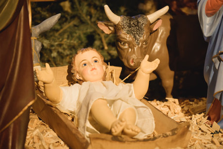 Close-up of the figurine of the baby Jesus raising his arms in front of the ox in the Christmas nativity sceneの写真素材
