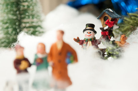 Miniature village scene in fake snow, with a focus on a cheerful snowmanの写真素材