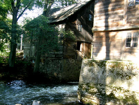architecture photo showing an old wooden water mill through which the river flows