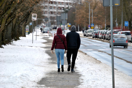 a photo of a couple of people walking together down the street in winterのeditorial素材