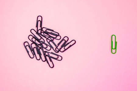 a handful of black paper clips and one green one.の写真素材