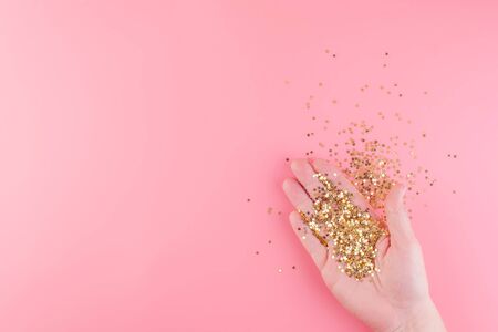 Female hand holds scattered gold stars confetti. Top view. Christmas card blank. Copy space and horizontal orientation.の写真素材