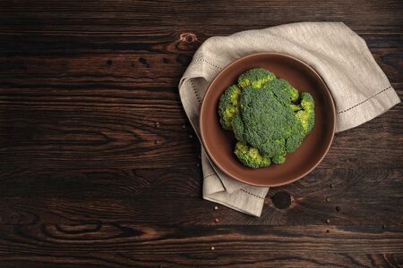 Broccoli. The head of cabbage lies in a deep plate. Top view. Dark light and rustic style. Copy space. Close up and horizontal orientation. の写真素材