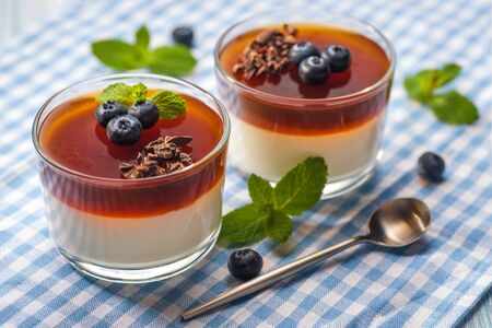 Traditional italian creamy dessert panna cotta. Dessert in a glass decorated with fresh blueberry and  jelly and mint leaves. Ready to eat. Close up and horizontal orientation. の写真素材