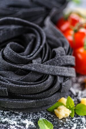 Black fettuccine. Homemade cooked pasta. Uncooked ingredients. Top view. Copy space. Close up and vertical orientation.の写真素材