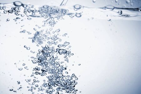 Water splashes with bubbles. Fluid in motion. Selective focus. Close up and horizontal orientation.