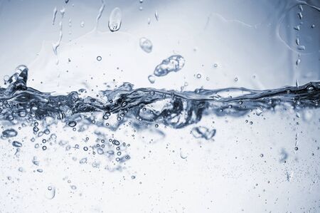 Water splashes with bubbles. Fluid in motion. Selective focus. Close up and horizontal orientation.