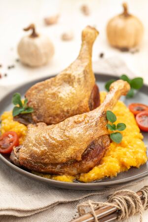 Roasted duck leg with pumpkin puree and fresh herbs. Large portion on a plate with a napkin on a wooden table. Ready to eat. Close up.
の写真素材