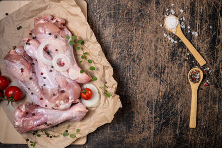 Semi-finished poultry products. Raw turkey wing surrounded by vegetables, spices and herbs on a dark wooden background. The poultry is ready to roast.の写真素材