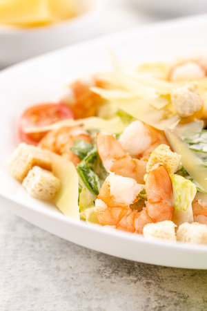 Shrimp salad with fresh vegetables, cheese and croutons. A large portion is served in a deep white plate. Ready to eat.の写真素材