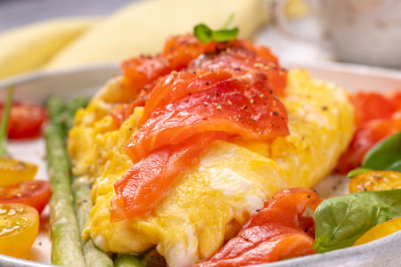 Fried eggs with green asparagus and salmon, cherry tomatoes and fresh spinach. Omelet with filling...
