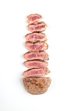 Fried cooked beef steak cut into pieces on a white plate. Top view.の写真素材