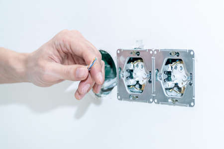 The craftsman installs an electrical outlet into the wall. Mounting the outlet in compliance with...