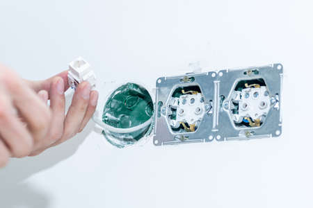 The craftsman installs an electrical outlet into the wall. Mounting the outlet in compliance with safety precautions. Close-up. Selective focus.の写真素材