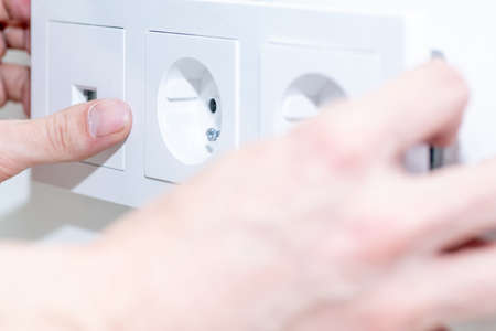 The craftsman installs an electrical outlet into the wall. Mounting the outlet in compliance with...