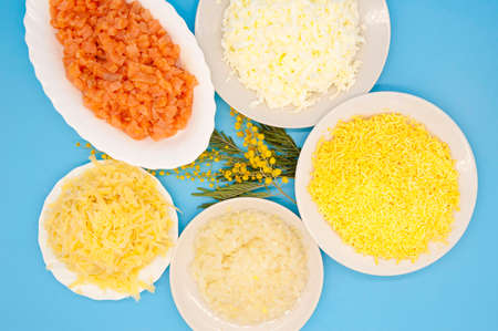 Cooking Mimosa salad. Layered salad of fish, eggs, cheese, butter, and boiled eggs. Traditional Russian salad for New Year celebrations. Flat lay top view.の写真素材