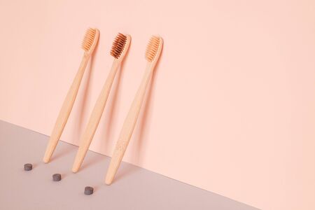 Bamboo toothbrush and dry tooth paste or toothpaste tablets on pink blue background. Zero waste,...
