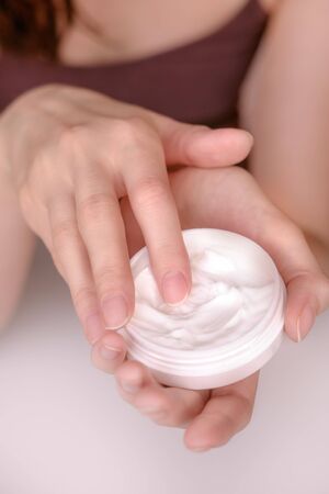Beautiful groomed womans hands with body and skin cream on a light background.の写真素材
