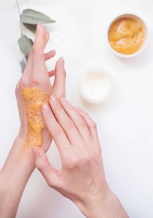 A young woman takes care of her hands with a scrub. Self care conceptの写真素材