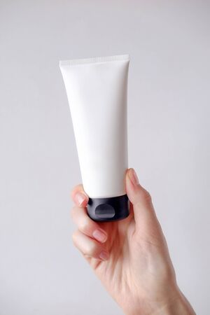 Young female hand holds minimalistic mockup cosmetic packaging. Mock-up for branding and label.の写真素材