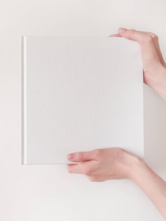 White book mockup. Square empty book. Album with clean pages in hands of woman. Clean book cover mockupの写真素材