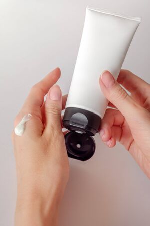 Young female hand holds minimalistic mockup cosmetic packaging, template for brandingの写真素材