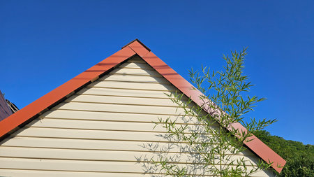 Wooden house with red roof and blue sky, closeup of photoの写真素材