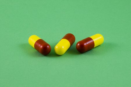 Three red and yellow pills, could be anything from vitamins to illegal drugs but actually cold and flu tablets!の写真素材