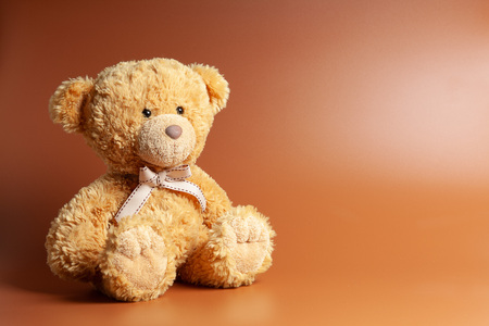 Soft warm cute brown teddy bear on color background. Isolated. Soft brown coffee background. Copy space for text.の写真素材