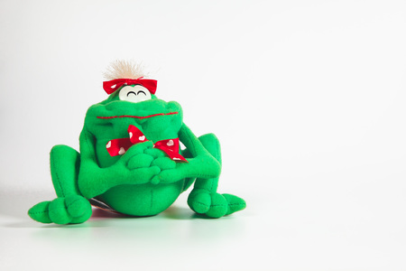 Happy green frog doll on color background. Isolated, green, red, white.の写真素材