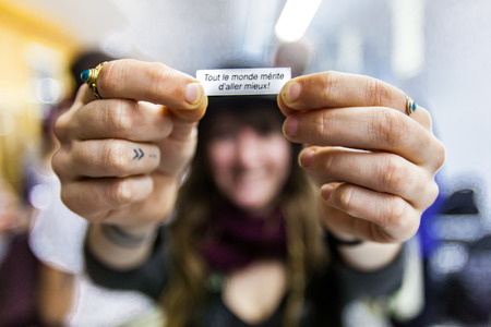 Girl shows a message to the camera with her both hands, it says Everyone deserve better in french