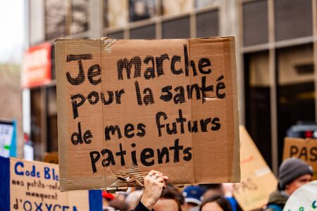 Environmentalists march for change. A French sign is seen closeup saying i'm walking for the health of my future patients as ecological demonstrators protest in an urban city street.の写真素材