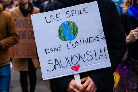 A French poster is viewed close up, saying only one in the universe, let's save it, held by an...