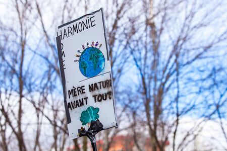 A closeup view of a French sign, reading harmony, home, mother nature first, on a city street as...