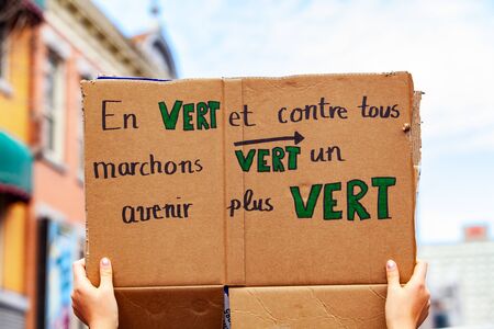 A closeup view of a French sign, saying in green and all against walks towards a greener future, held by an ecological activist during a protest in a city center.の写真素材