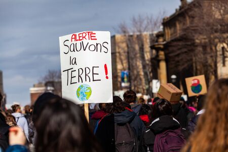 A close-up view of a French sign reading Alert, save our planet as a packed crowd of environmental...