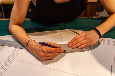 A closeup view of a female fashion designer working on technical illustrations on studio table....