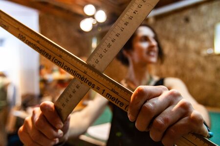 A female fashion worker stands inside an atelier, she holds two metric rulers, used to measure fabrics and sketch new designs.の写真素材