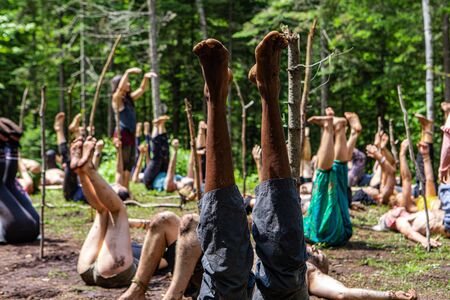 Diverse people enjoy spiritual gathering A multiethnic group of people are seen with bare legs raised in air during a yogic exercise class in natural surroundings.の写真素材