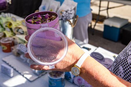 Fresh food at outdoor farmer's market. Aromatic rose essence is seen in a pink tin, closeup in the...