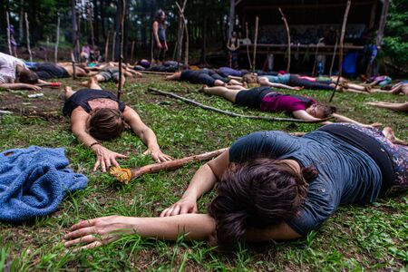Diverse people enjoy spiritual gathering A multigenerational group of people are seen meditating in the forest, lying on the ground at a native cultures retreat with room for copy.の写真素材